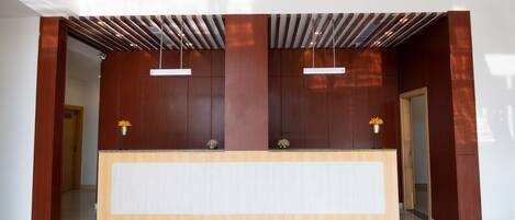 A reception desk with a wooden finish, two pendant lights, and a clean, modern design.