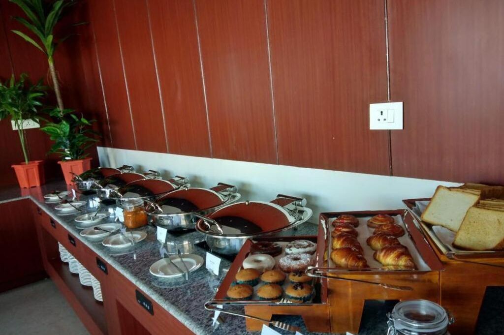 Un buffet proposant une variété d’aliments, notamment des pâtisseries, du pain et des boissons.