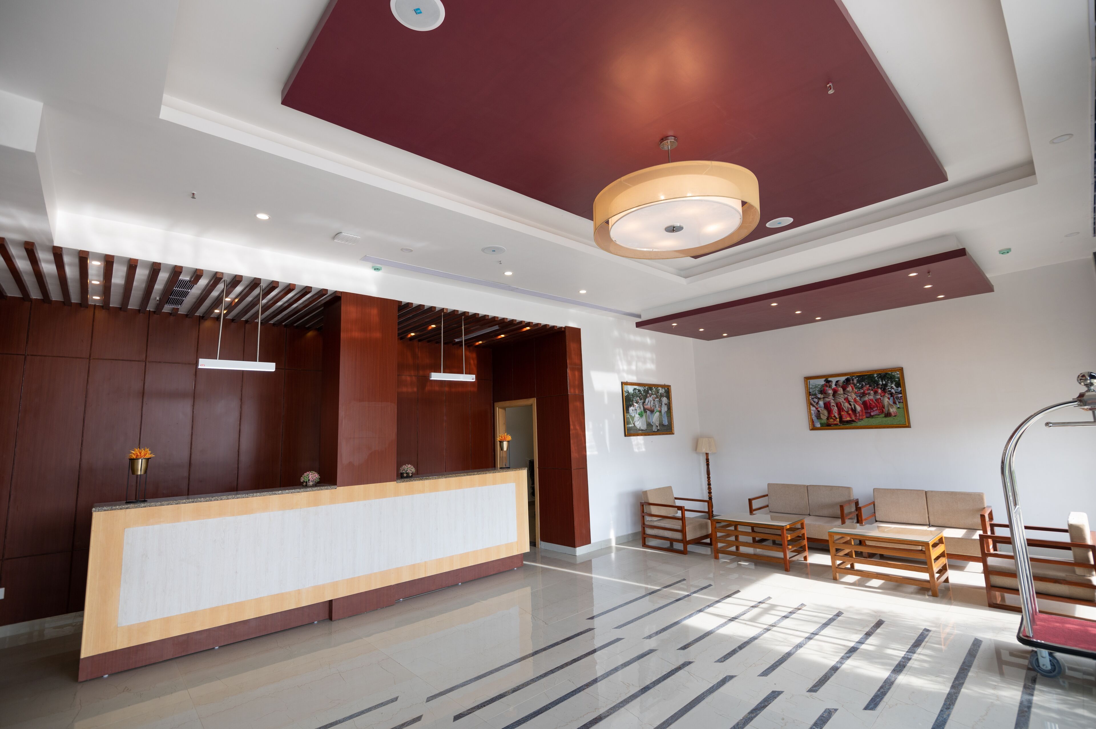 A modern reception area with a wooden reception desk, seating area with sofas and chairs, and a large painting on the wall.