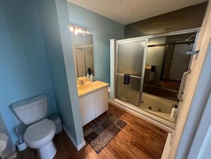 Et badeværelse med toilet, vask, spejl og brusekabine i glas.
