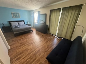 A bedroom with a bed, bedside tables, a dresser, a mirror, and a window with curtains.