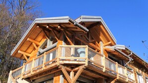 Une cabane en bois dotée d’un balcon, de grandes fenêtres et d’un pilier en pierre.