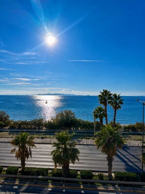 A coastal road with palm trees, a clear sky, and the sun shining over the sea. - Adelos Coastal Chic by the Sea - Athens Riviera (Alimos)