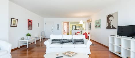 Un salon moderne avec un canapé blanc, une table basse et un téléviseur posé sur un meuble blanc.