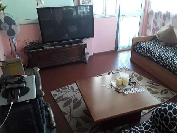 Ein Wohnzimmer mit Fernseher, Sofa und Couchtisch mit Kerzen.