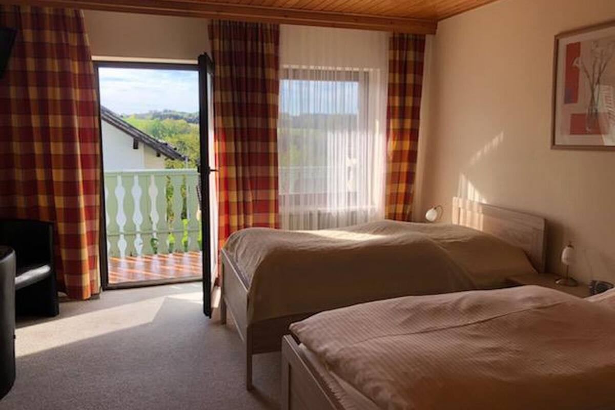 Een hotelkamer met twee bedden, een bureau en een balkon met uitzicht.