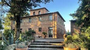A rustic stone building with a brick facade, a set of stone steps leading to the entrance, and potted plants around the area.