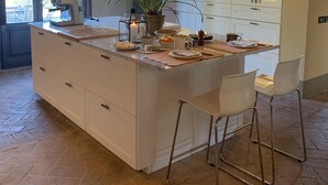 A modern kitchen with a large island, white cabinetry, and a hanging pendant light.