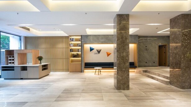 A modern lobby with a reception desk, seating area, and a staircase. - Ramada Encore by Wyndham Qingdao Shinan (Qingdao)
