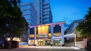 A hotel with a modern facade, a prominent 'Encore' sign, and a well-lit entrance. - Ramada Encore by Wyndham Qingdao Shinan (Qingdao)
