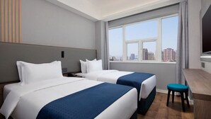 A hotel room with two beds, a desk, and a large window offering a city view. - Ramada Encore by Wyndham Qingdao Shinan (Qingdao)
