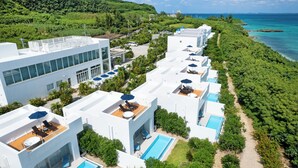Un complex turístic amb diversos edificis blancs, piscines exteriors i vistes al mar.