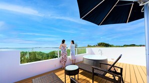 A balcony with two people overlooking a scenic view, a round table, and a small round chair. - Blue Ocean Hotel & Resort Miyakojima (Miyakojima)
