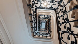 Een statige trap met gedetailleerde zwarte metalen leuningen en een glazen balustrade in het midden.