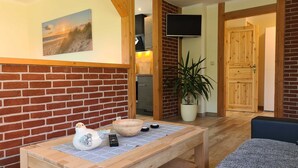 Ein Zimmer mit Backsteinwand, einem Holztisch mit Vogel-Skulptur, einer Schüssel und einer Fernbedienung.