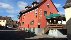 Un edificio rojo con un letrero que dice "GASTHOF ENGEL" y una escalera que conduce a una zona cubierta.
