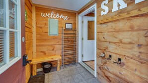 Un interno in legno con un cartello che dice 'welcome', una panca, un appendiabiti e una porta con scritto 'SKI'.