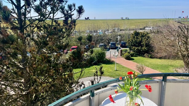 Uma varanda com vista para um estacionamento e um campo gramado.
