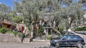 A residential street with houses, a car parked on the side, and trees. - Milans Apartments (Pržno)