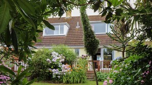 Une maison avec un jardin à l’avant, une fenêtre visible et une porte.
