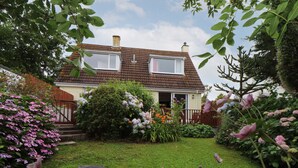 Une maison avec un jardin, une pelouse et un petit étang.