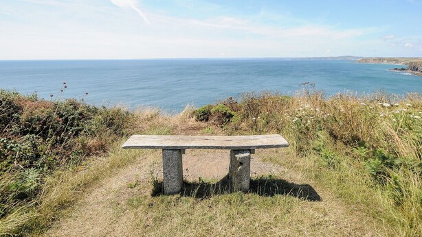 Un banc de pierre offrant une vue imprenable sur la côte, avec la mer et la terre qui s’étend au loin.