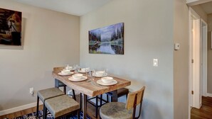 A dining area with a wooden table set for four, two chairs, and a painting of a forest scene on the wall. - A Ridge above the Rest!  New Remodel and High End Upgrades (Breckenridge)