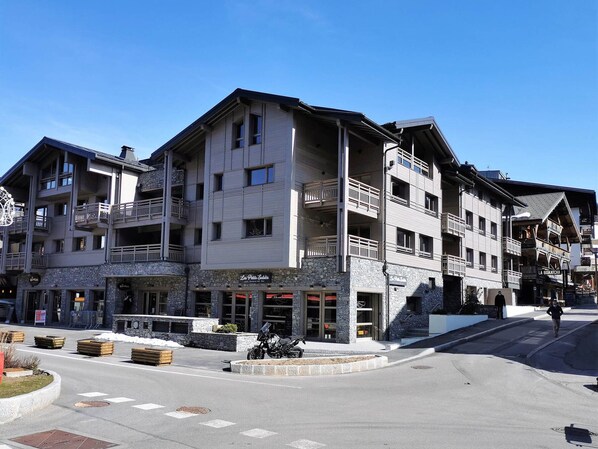 A multi-story hotel with balconies, a stone facade, and a ski resort sign.