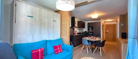 A compact living space with a sofa, a dining table, and a kitchenette.