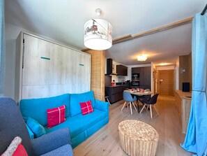 A compact living space with a sofa, a dining table, and a kitchenette.