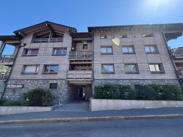 A multi-story building with balconies, a stone facade, and a sign indicating a restaurant.