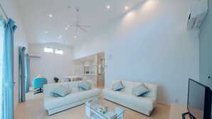 A modern living room with two white sofas, a glass coffee table, and a ceiling fan. - Villa Capri Miyakojima (Miyakojima)