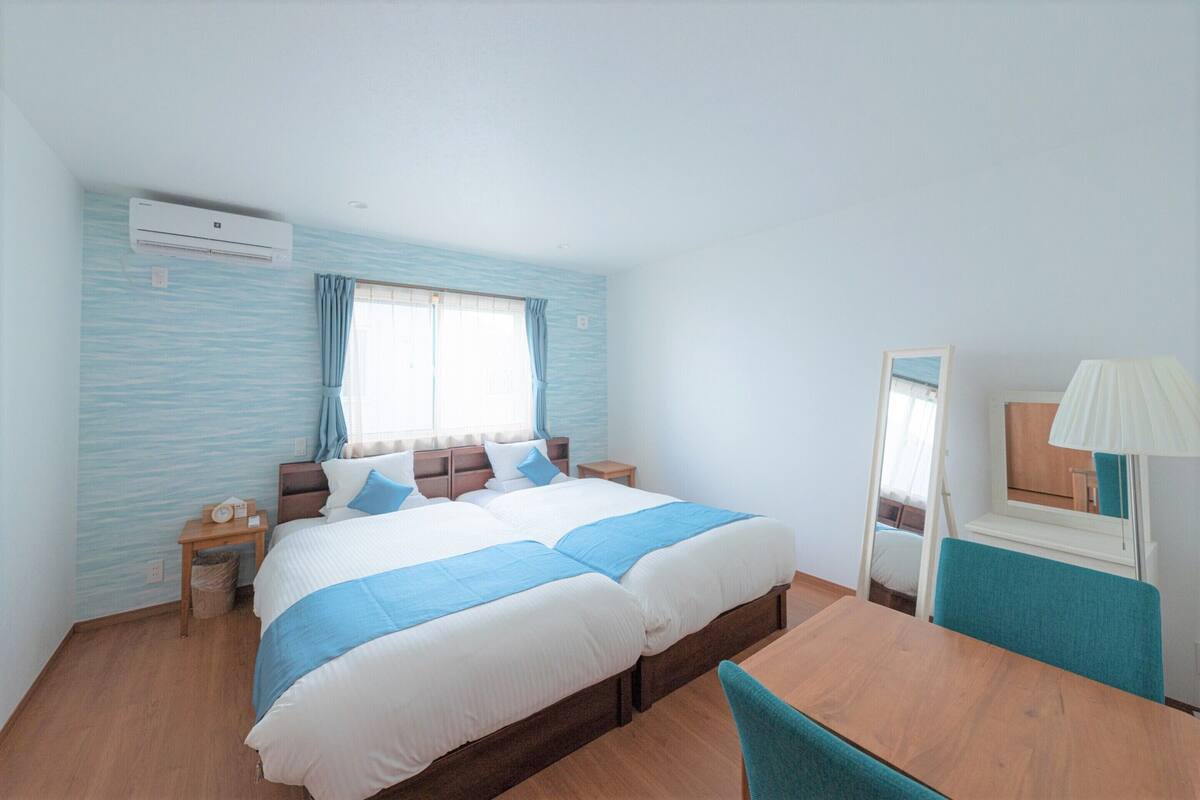 A bedroom with a bed, bedside tables, a mirror, and a window with curtains.
