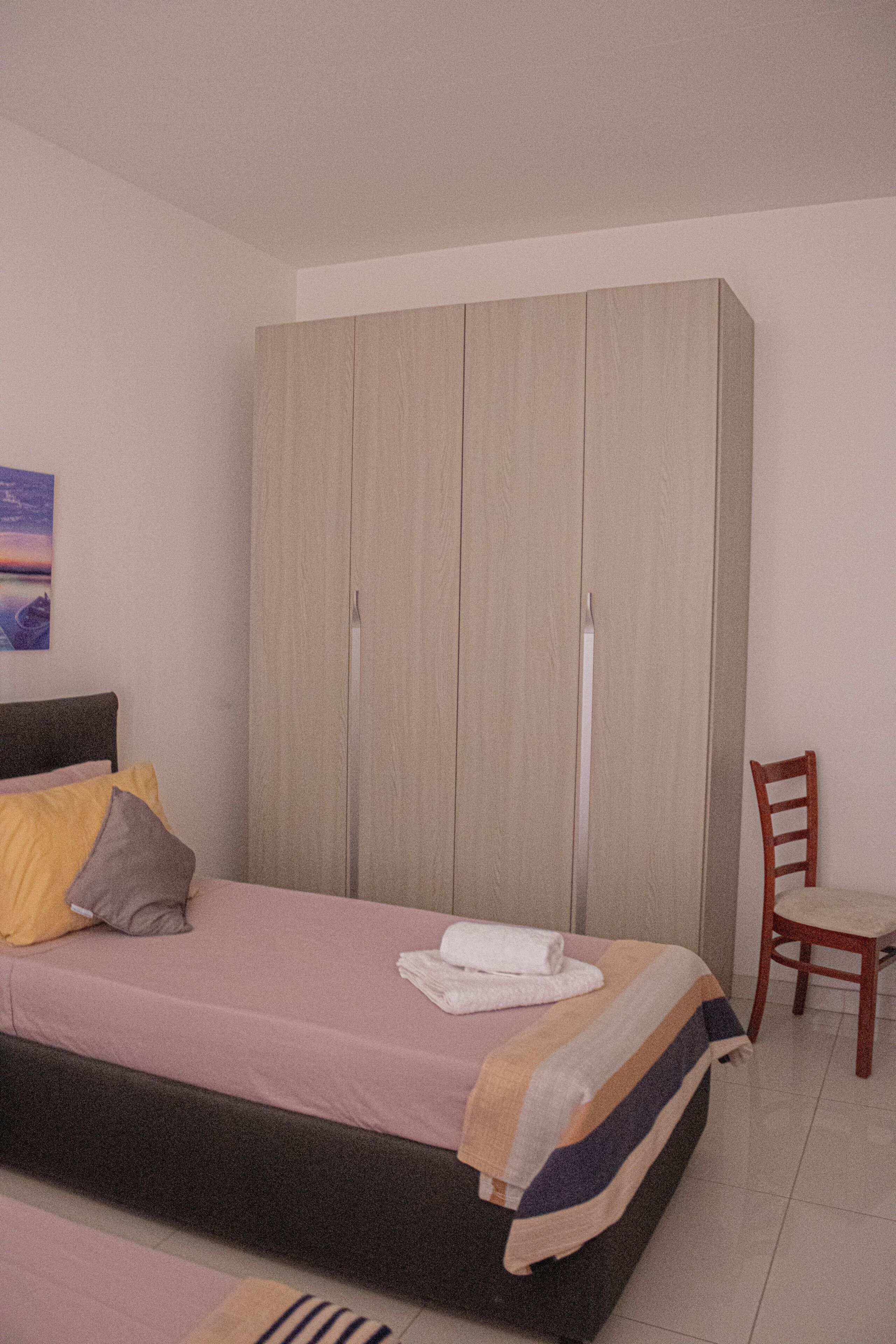 Een slaapkamer met een bed, een kast en een stoel.