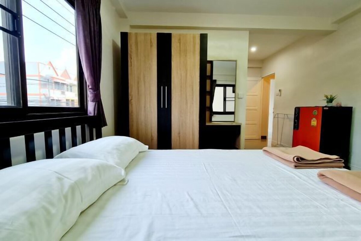 Una habitación de hotel con una cama, un armario, un escritorio y un mueble rojo.