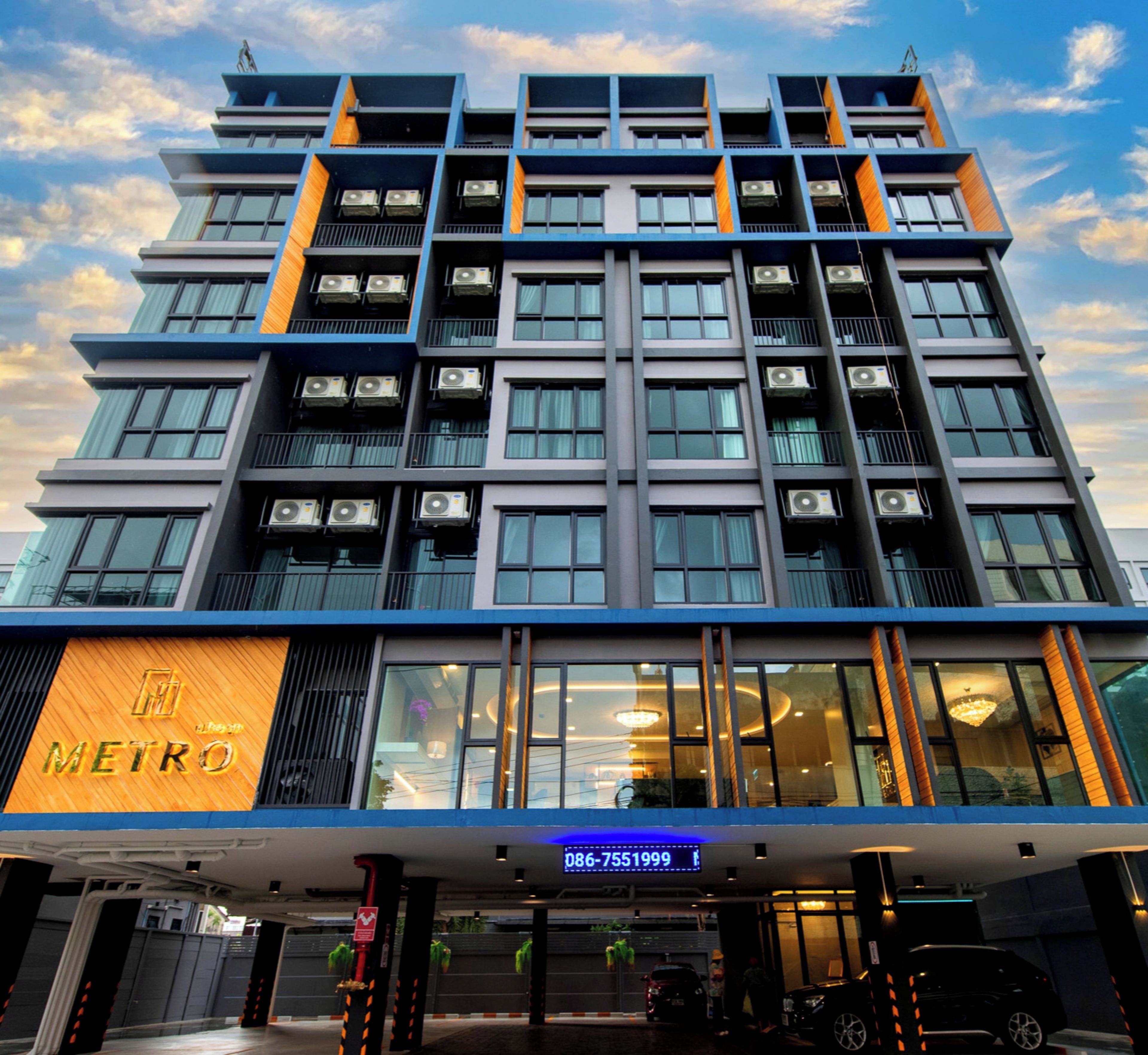 A modern building with multiple floors, large windows, and air conditioning units.