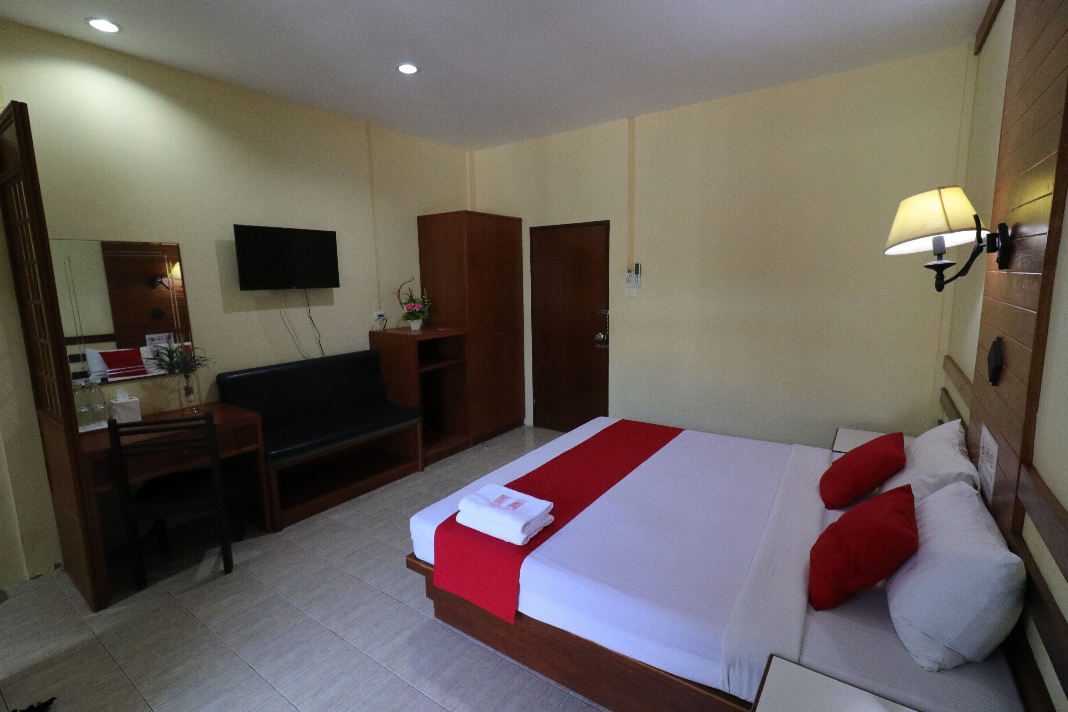 A hotel room with a bed, a desk, a chair, a TV, and a wardrobe.