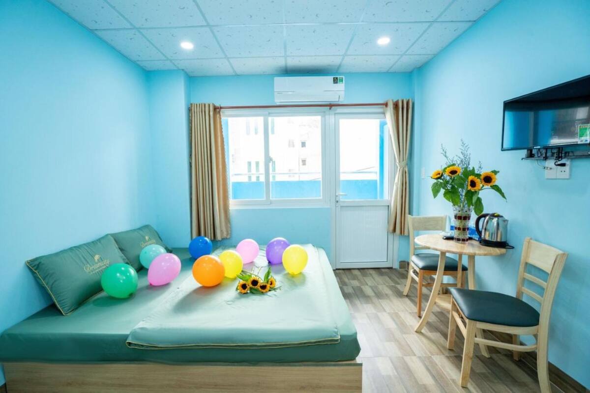 A room with a bed, a small table with chairs, a TV, and a window with curtains.