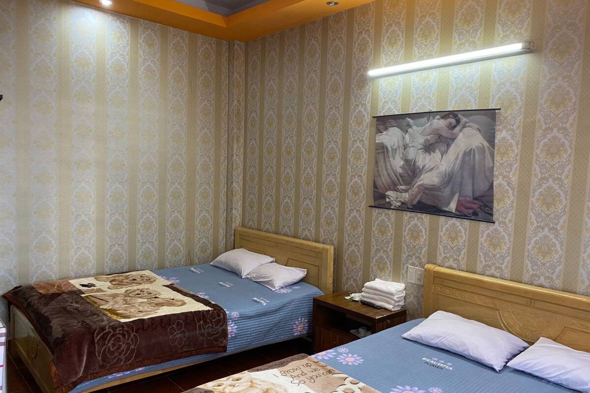 A hotel room with two beds, a nightstand, and a wall-mounted picture.