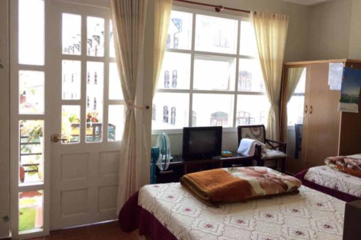A room with a bed, a desk, a chair, and a television. There is a window with curtains and a door.