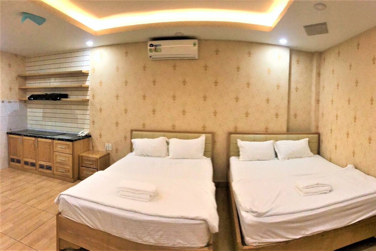 Ein Hotelzimmer mit zwei Betten, einer Küchenzeile und einer Klimaanlage.