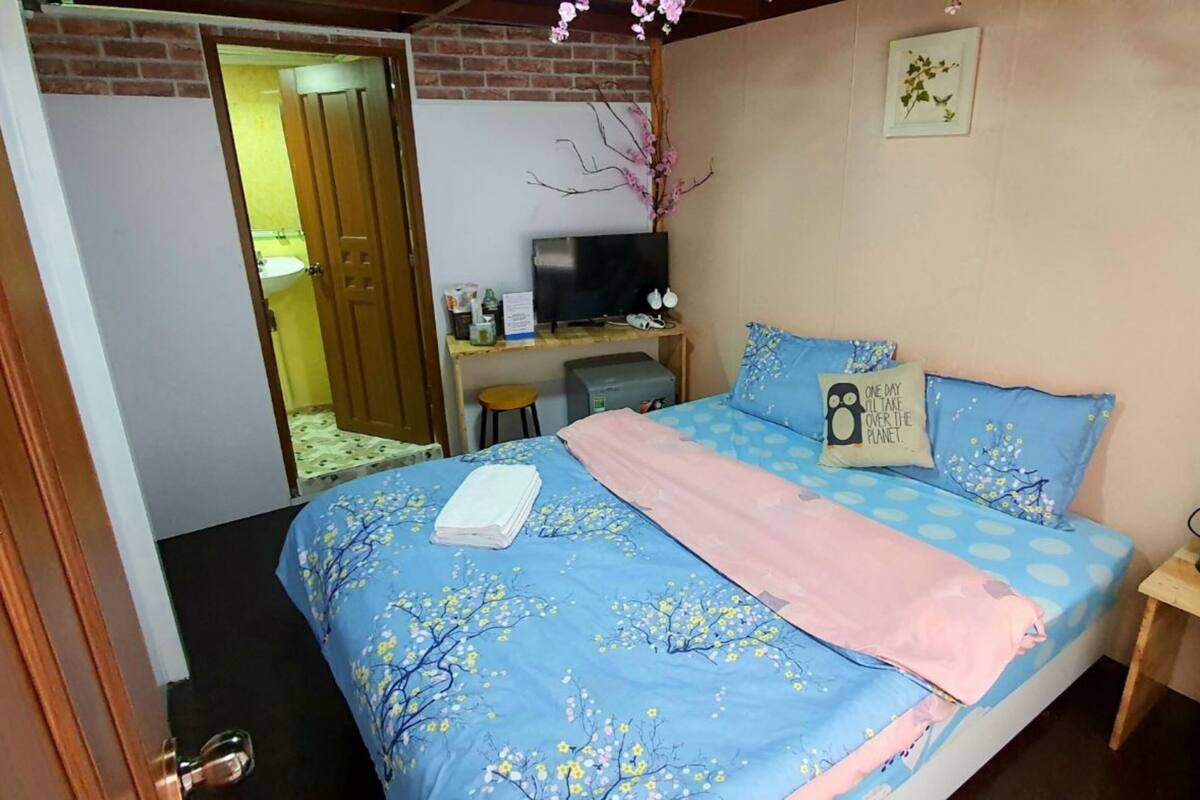 A bedroom with a bed, a television, and a desk.
