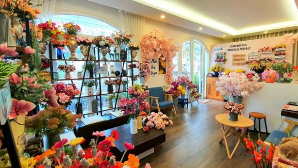 A floral shop with shelves of flowers, a teddy bear, and a sign with foreign text. - Pho Hoa Boutique Villa (Cam Ly - Da Lat)