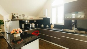 A modern kitchen with a black countertop, stainless steel appliances, and a window providing natural light. - Pho Hoa Boutique Villa (Cam Ly - Da Lat)