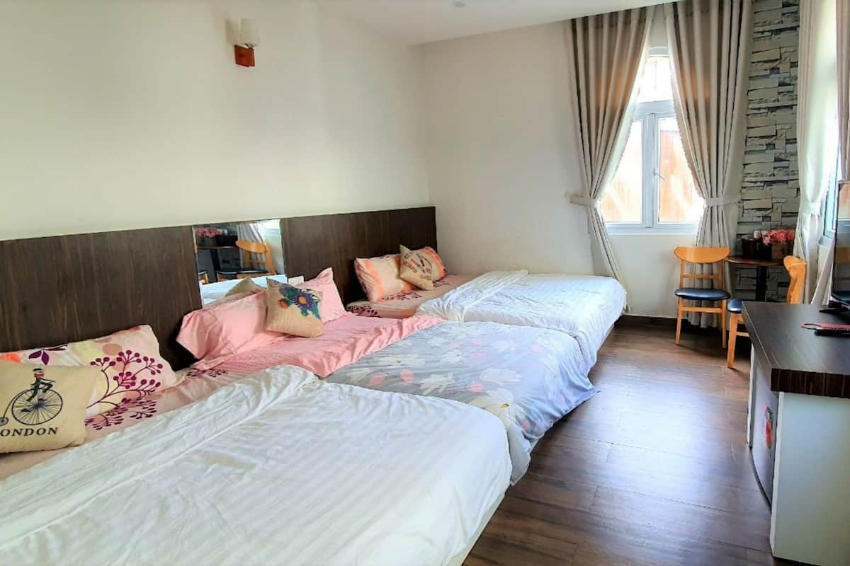 A hotel room with two beds, a desk with a television, and a window with curtains.
