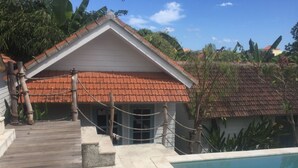 A building with a red-tiled roof, a wooden deck, and a pool. - Ms Snack Point Bed & Breakfast (Canggu)