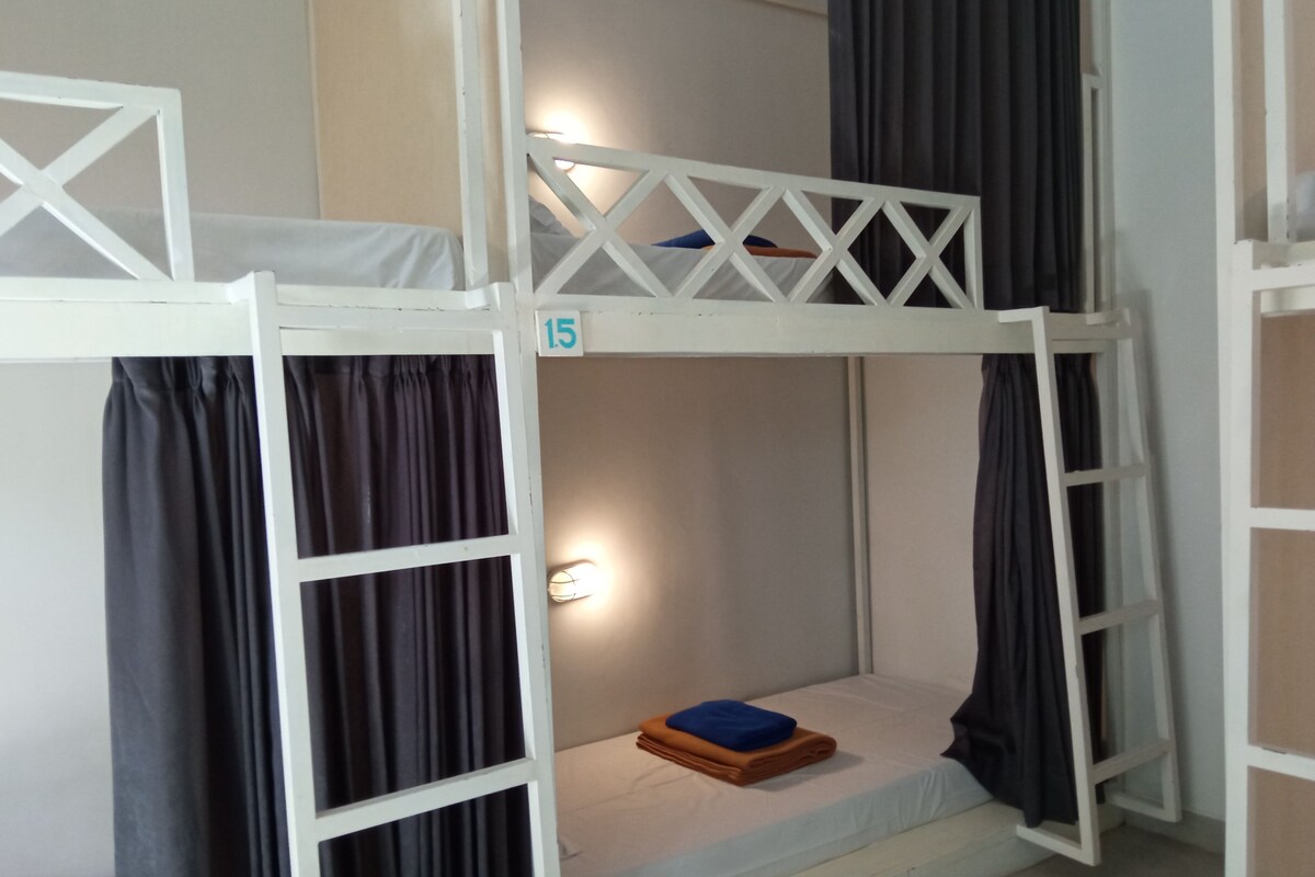 A bunk bed with a ladder, a small bedside table, and a wall-mounted light.
