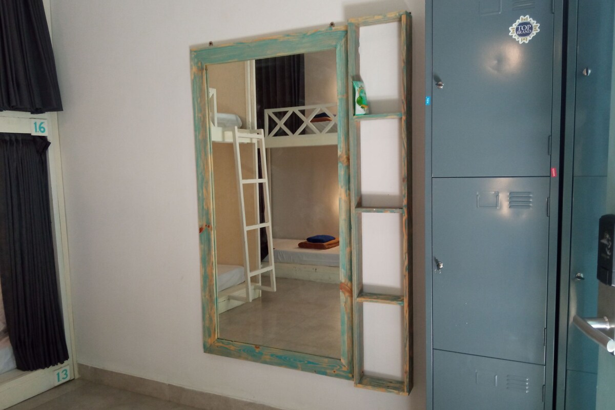 Une chambre avec un lit superposé, une armoire et un miroir au mur.