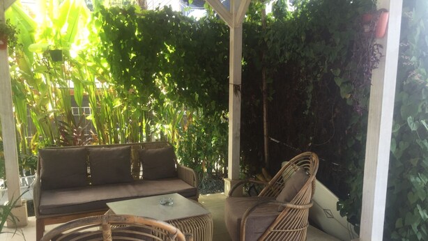 A covered patio area with a sofa, two wicker chairs, and a small table. - Ms Snack Point Bed & Breakfast (Canggu)