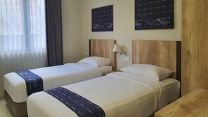A hotel room with two single beds, a wooden headboard, a nightstand, a lamp, and two wall-mounted artworks. - Ms Snack Point Bed & Breakfast (Canggu)